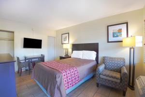 Habitación de hotel con cama, silla y escritorio. en Sunrise Inn by OYO Titusville FL, en Titusville