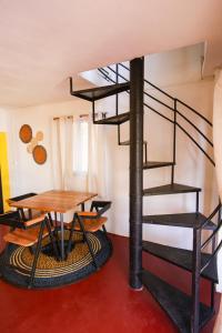 a spiral staircase in a room with a wooden table and a tableablish at Le jardin des délices in Mahajanga