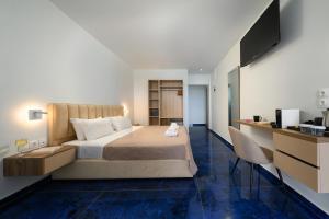 Dormitorio con cama, escritorio y TV en Ninos Grand Beach Resort, en Kastrosikia