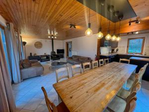 comedor y sala de estar con mesa de madera y sillas en Le Bercail, en Somme-Leuze