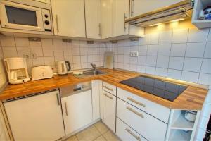 eine kleine Küche mit einer Spüle und einer Mikrowelle in der Unterkunft Ferienpark - Haus H, App 0H0709 in Heiligenhafen