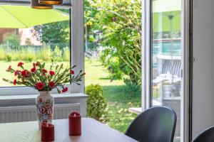 un vase avec des fleurs sur une table devant une fenêtre dans l'établissement Ferienwohnung "Sonnenschein", à Tarnewitz