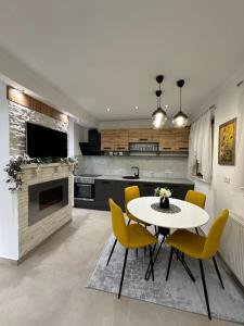 Una cocina con una mesa blanca y sillas amarillas. en Apartmani Lana, en Vlašić