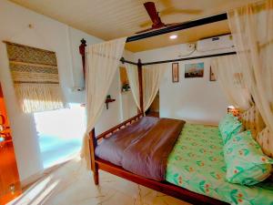 ein Schlafzimmer mit einem Himmelbett und einem Fenster in der Unterkunft EcoZen Holiday Rooms in Agonda