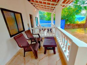 eine Veranda mit Stühlen und einem Holztisch auf dem Balkon in der Unterkunft EcoZen Holiday Rooms in Agonda