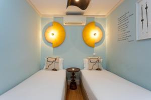 two beds in a room with lights on the wall at Casas da Baixa - Jules & Madeleine in Lisbon