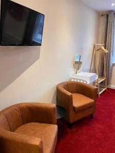 a living room with two chairs and a flat screen tv at St Benedicts Apartments in Norwich