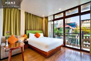 ハノイにあるHANZ Artisan Lakeview Hotel Hanoiのベッドとバルコニー付きのホテルルーム