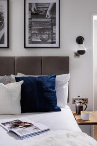 a bed with a blue pillow and a book on it at Stunning Central Plymouth Studio Apartment - Sleeps 2 - Habita Property in Plymouth