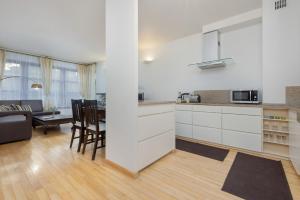 une cuisine avec des placards blancs et un salon dans l'établissement Sienna Family Apartment in the Center of Warsaw by Renters, à Varsovie