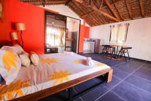 a bedroom with a large bed with a red wall at Le jardin des délices in Mahajanga