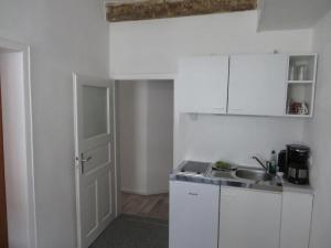 a kitchen with white cabinets and a sink and a door at Pfieffetalblick in Spangenberg