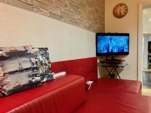 uma sala de estar com um sofá vermelho e uma televisão em Comfy rooms. Shared East London Homestay. em Londres
