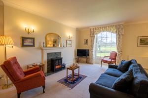 a living room with a couch and a fireplace at Garden Wing, Redisham Hall in Beccles