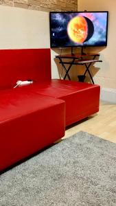 a red couch in a room with a flat screen tv at Comfy rooms. Shared East London Homestay. in London