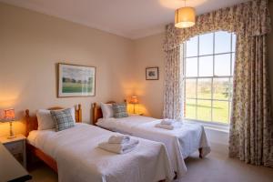 two beds in a room with a window at Garden Wing, Redisham Hall in Beccles