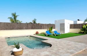 una piscina en un patio trasero con 2 sillas azules en Villa Montenmedio 1, en El Soto