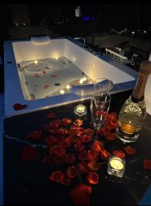 a bath tub with a bottle and glasses and roses at SUITE SPACE by concept italy in Casoria