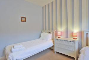 a bedroom with a bed and a nightstand with two lamps at Happy Days in Southwold