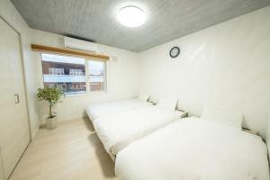 2 Betten in einem Zimmer mit einer Uhr an der Wand in der Unterkunft furano ski rabi in Furano