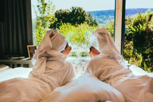 two women sitting in bed looking out a window at TinyLodge 5 in Heilbad Heiligenstadt