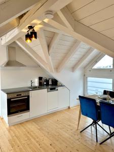 ブレゲンツにあるZentrale Wohnung mit Dachterasseのキッチン(白いキャビネット、テーブル、椅子付)