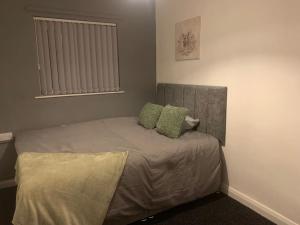 a bedroom with a bed with two green pillows at 2 Bedroom Flat room 13 in Stockton-on-Tees