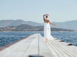 Sofitel Golfe d'Ajaccio Thalassa Sea & Spa في أجاكسيو: امرأة ترتدي ثوب أبيض تقف على الرصيف