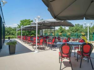 an outdoor patio with tables and chairs and umbrellas at ibis Antibes Sophia-Antipolis in Valbonne