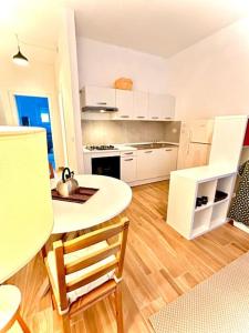 uma cozinha com uma mesa branca, uma mesa e cadeiras em nuovo appartamento a due passi dal centro em Turim