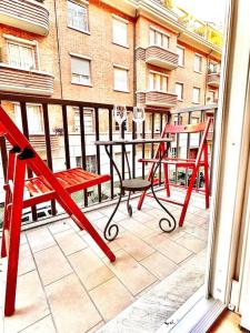 un balcone con 2 sedie rosse, un tavolo e un edificio di nuovo appartamento a due passi dal centro a Torino