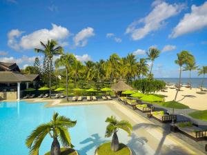 einen Pool mit Stühlen und Sonnenschirmen in einem Resort in der Unterkunft Sofitel Mauritius L'Imperial Resort & Spa in Flic-en-Flac
