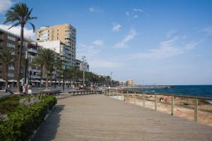 eine Promenade entlang eines Strandes mit Gebäuden und dem Meer in der Unterkunft Homely Apartments Vitoria in Torrevieja
