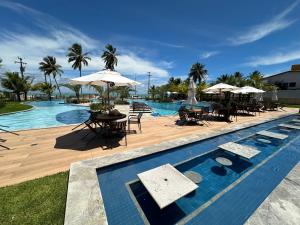 a swimming pool with tables and umbrellas and chairs and a pool at Blue Beach Beira Mar in Cabedelo
