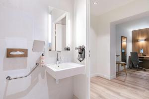 een witte badkamer met een wastafel en een bureau bij Best Western Plus 61 Paris Nation Hotel in Parijs