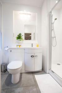 a white bathroom with a toilet and a mirror at Urban Living's - King Edward Luxury Suites in Windsor