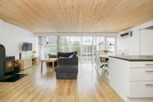 cocina y sala de estar con sofá y mesa en Nice Summer House , Spa, Sauna, Wood Stove, Tv, en Sønderby