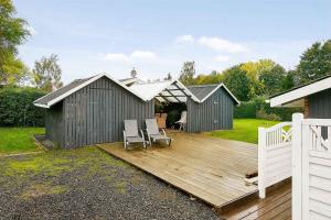 una terraza de madera con 2 sillas y una casa en Nice Summer House , Spa, Sauna, Wood Stove, Tv, en Sønderby