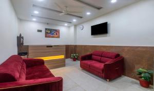 a living room with two red chairs and a tv at Itsy By Treebo - Krishna Residency, Govardhan Chauraha in Mathura