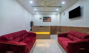 a living room with two red couches and a flat screen tv at Itsy By Treebo - Krishna Residency, Govardhan Chauraha in Mathura