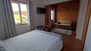 Porto Pim Guest House في أورتا: غرفة نوم بسرير وكرسي ونافذة