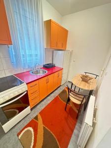 cocina con armarios naranjas, fregadero y mesa en Apartment Boulevard, en Belgrado