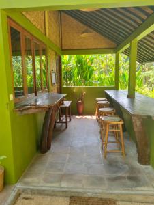 um pátio com paredes verdes, mesas e bancos em eco beach house bali em Penginuman