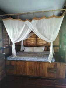 um quarto com uma cama de dossel e cortinas brancas em eco beach house bali em Penginuman
