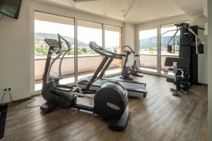a gym with two treadmills and ellipticals in front of a window at Hotel Schlossberg Wehingen in Wehingen