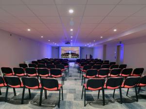 a large room with chairs and a projection screen at Mercure Fribourg Centre Remparts in Fribourg