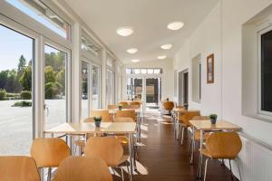 a restaurant with tables and chairs and windows at Amedia Express Sattledt, Trademark Collection by Wyndham in Sattledt