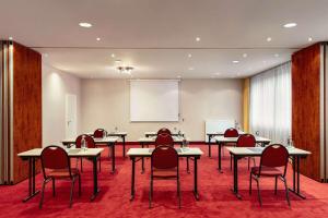einen Konferenzraum mit Tischen, Stühlen und einem Whiteboard in der Unterkunft Amedia Frankfurt Russelsheim Trademark Collection by Wyndham in Rüsselsheim