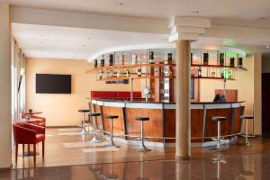 a bar in a building with stools in a room at Amedia Frankfurt Russelsheim Trademark Collection by Wyndham in Rüsselsheim