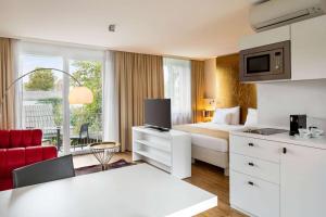 a hotel room with a king sized bed and a kitchen at Amedia Luxury Suites Graz, Trademark Collection by Wyndham in Graz
